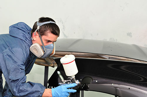 20442786 – worker painting car parts in a paint booth